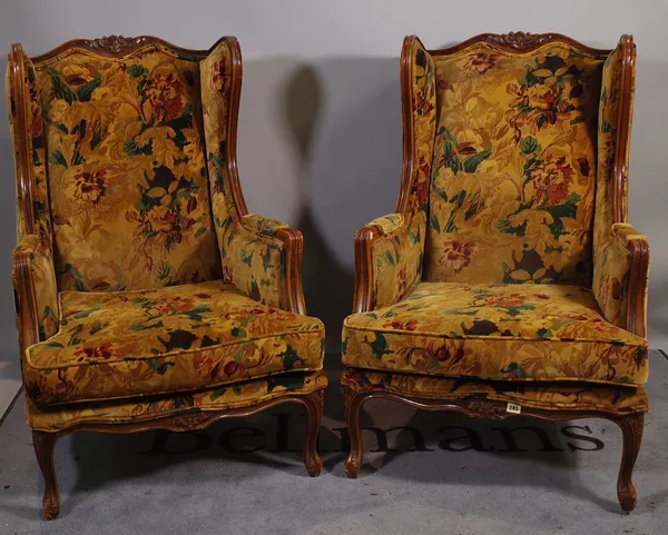 A pair of 20th century French stained beech wingback armchairs on cabriole supports, 70cm wide x 105cm high, (2).