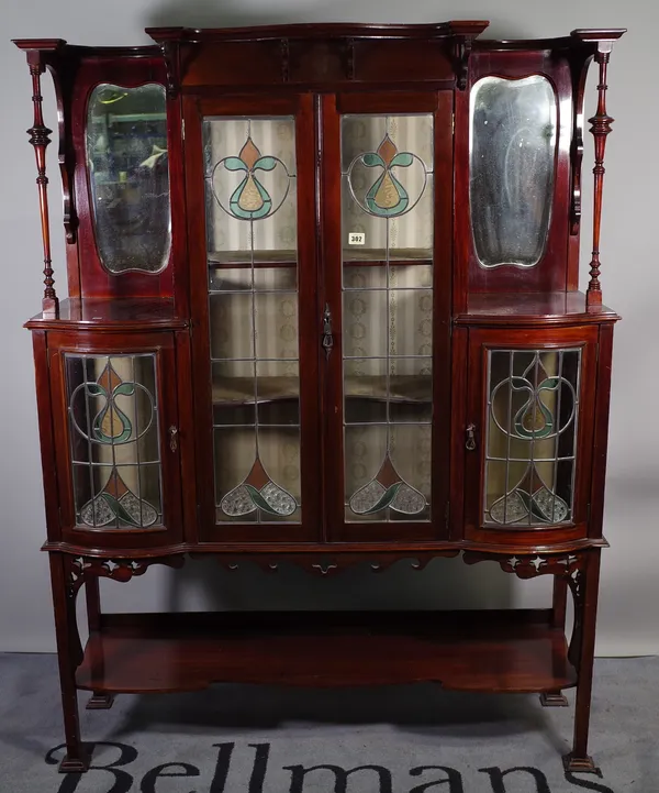 A late Victorian mahogany glazed display cabinet, with Art Nouveau stained glass motifs, resting on square supports, united by undertier, 120cm wide x