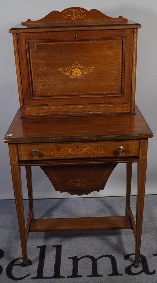 An Edwardian mahogany inlaid writing desk of unusual form, the fall enclosing a fitted interior over a two tier base with pull-out basket, 61cm wide x