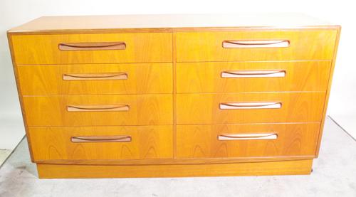 G Plan; a 20th century stained beech chest of eight single drawers, on plinth base, 142cm wide x 76cm high.