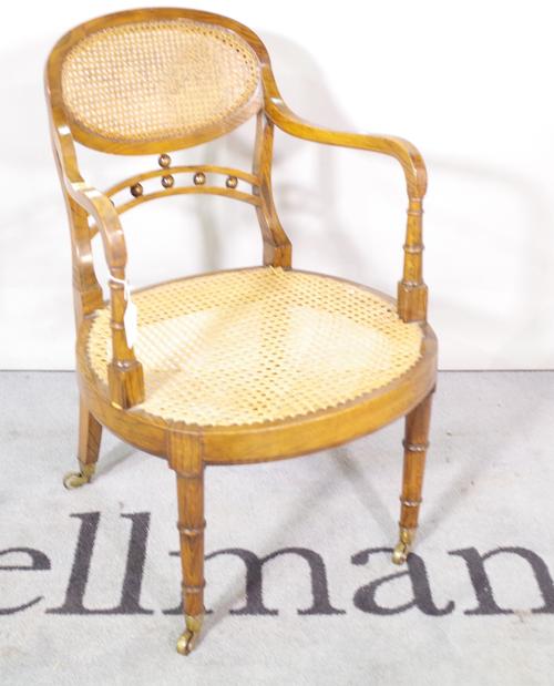 A Victorian faux painted rosewood open armchair, with cane back, on ring turned tapering supports.