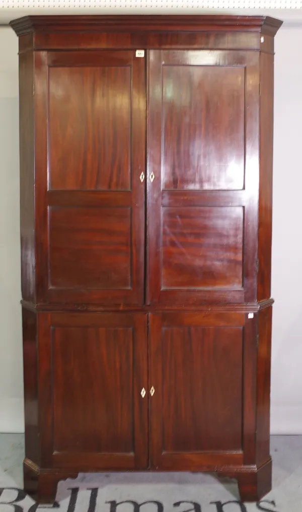 A George III mahogany double height corner cupboard with panelled doors, 113cm wide x 198cm high.