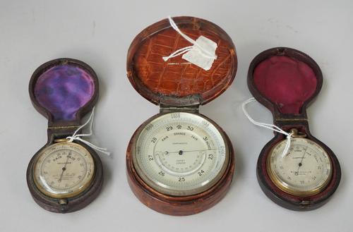 An Asprey brass cased table barometer, circa 1900, with thermometer compendium in a crocodile skin case (7cm diameter), a Short & Mason pocket baromet