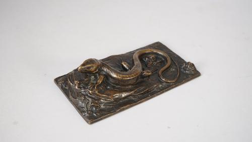 A relief cast bronze lizard, early 20th century, resting on a rocky outcrop on an integral naturalistic rectangular base, unsigned, 18cm wide.