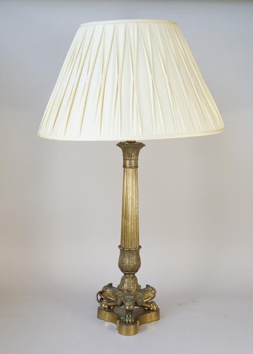 An Ormolu table lamp of fluted column form raised on three lion paw feet and a triform shaped base with pleated cream silk shade, 88cm high overall.