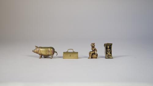 A novelty brass cigar cutter, early 20th century, modelled as a naked woman, seated on a chamber pot (3cm), another similar modelled as a naked woman