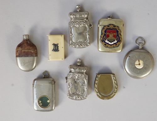 A white metal gadget vesta, early 20th century, the body inset with three dice (5.5cm high), a white metal 'pocket watch' vesta and six further novelt