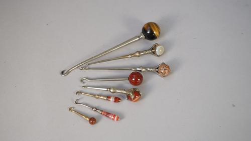 A miniature silver button hook with a striated agate handle (6cm), another similar, five larger white metal button hooks each set with a hardstone sph