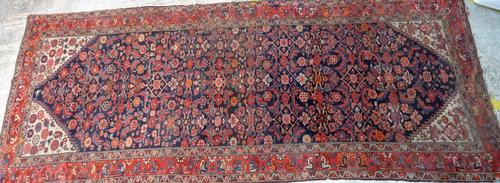 A Fereghan runner, Persian, the dark indigo field with an all over herate design, ivory spandrels; a madder main border with pairs of stylized tulips,