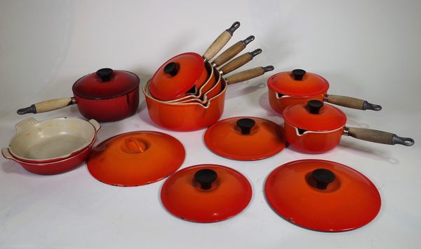 Six Le Creuset volcanic orange saucepans with lids, sizes 22, 20,18,16,16,14, another saucepan, size 18 in red, and two volcanic orange dishes, (9). S