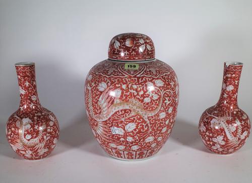 A late 19th/ early 20th century Asian red and white ginger jar decorated with dragons, 30cm high x 23cm wide, and a pair of matching bottle vases, S3T