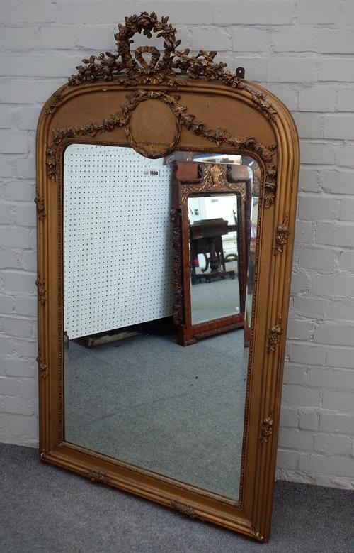 A 19th century gilt framed arch top over mantel mirror, with ribbon tied floral crest and bevelled mirror plate, 85cm wide x 147cm high.