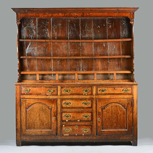A George III mahogany banded oak dresser, the enclosed three tier shelf back with six spice drawers, the base with six short drawers flanked by cupboa