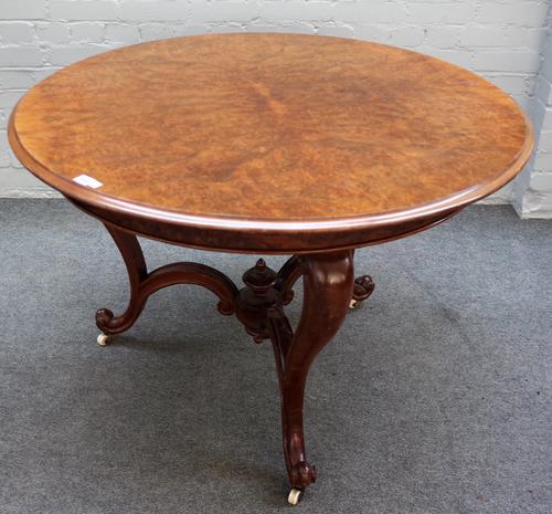 A Victorian figured walnut circular table on three scroll supports, united by shaped stretcher, 105cm diameter x 75cm high.