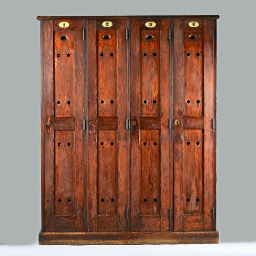 A stained pitch pine four door locker unit, on plinth base, 140cm x 177cm high. Illustrated.