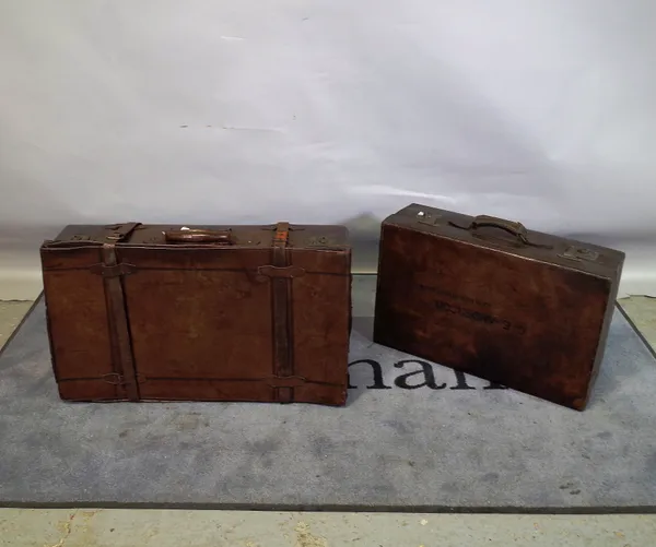 An early 20th century leather suitcase, 80cm wide x 23cm high, and another smaller, 67cm wide x 20cm high, (2).