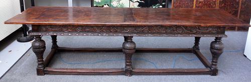 A 17th century style oak refectory table, with carved frieze and bulbous supports united by perimeter stretcher, 85cm wide x 310cm long.