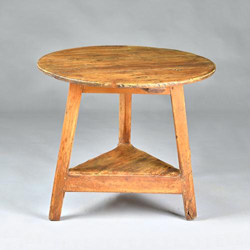 An early 19th century pine cricket table, on three splayed supports united by platform undertier, 75cm diameter x 64cm high. Illustrated.