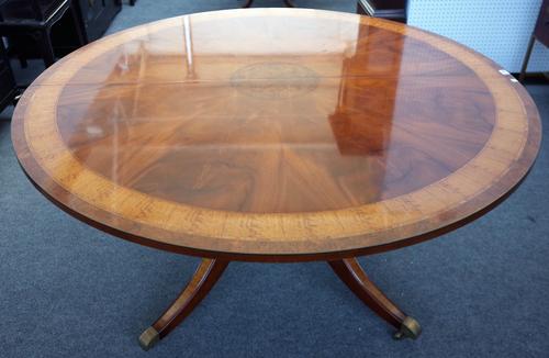 Probably Brights of Nettlebed; a 20th century figured walnut and satinwood banded mahogany circular centre table, on four turned columns and downswept