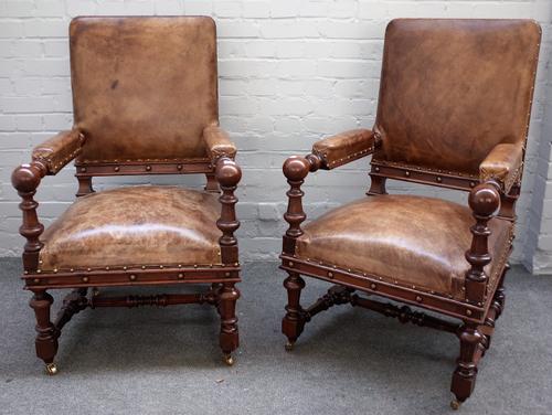 A pair of Victorian brown leather upholstered oak framed open armchairs, with ball finials on turned supports, 65cm wide x 107cm high.