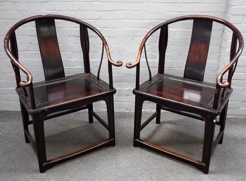 A pair of 19th century Chinese hardwood horseshoe back armchairs, with solid seats on rounded supports, 74cm wide x 105cm high.