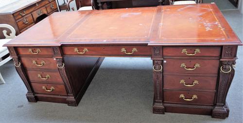 After Chippendale, a modern mahogany pedestal desk with nine frieze drawers and opposing cupboards, mounted with lions' head busts, 214 cm wide x 107