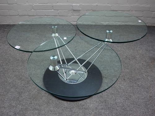 A 20th century occasional table with three glass tiers, on revolving ebonised base, 42cm high, each tier approx. 52cm diameter.