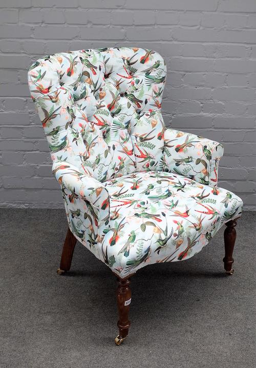 A Victorian style button back easy armchair with Bird of Paradise upholstery, on turned supports, 69cm wide x 96cm high.