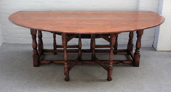 A 17th century style oak wake table, the oval top on baluster supports, 229cm wide x 75cm high.