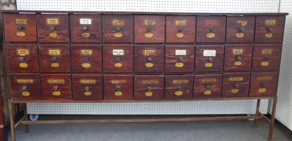 A stained pine apothecary cabinet with three rows of nine drawers, on metal stand, 221cm wide x 114cm high x 28cm deep.