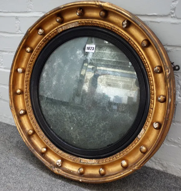 A Regency gilt framed circular convex wall mirror with ebonised slip, 57cm diameter.