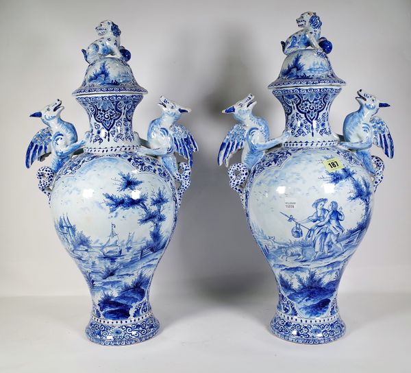 A pair of 20th century Dutch Delft blue and white two handled baluster vases and covers, figurative and landscape panels, dragon handles, 56cm high, (