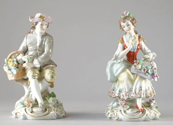 A pair of Sitzendorf porcelain figures, 20th century, modelled as male and female flower sellers, each seated on a gilt 'C' scroll base, blue printed