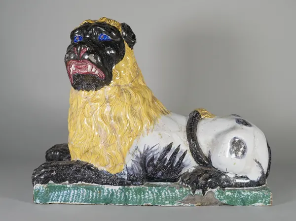 A French faience figure of a recumbent lion, probably Luneville, late 18th/early 19th century, with blue eyes, yellow mane and on a rectangular green