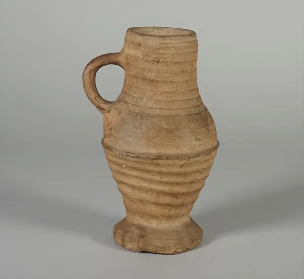 A Rhineland pottery mug, probably 15th century, of ribbed baluster form with lobed foot, (a.f), 15.5cm. high.