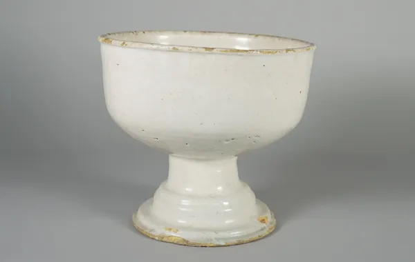 An unusual white tinglazed earthenware footed bowl, possibly German, 18th century, raised on a short stem and circular stepped base, 18.5cm. high.