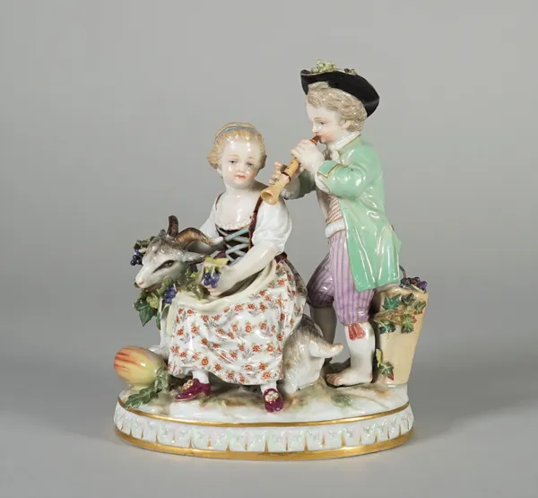 A Meissen group of two children representing Autumn, late 19th/early 20th century, modelled with a boy playing a pipe standing over a girl with a bran