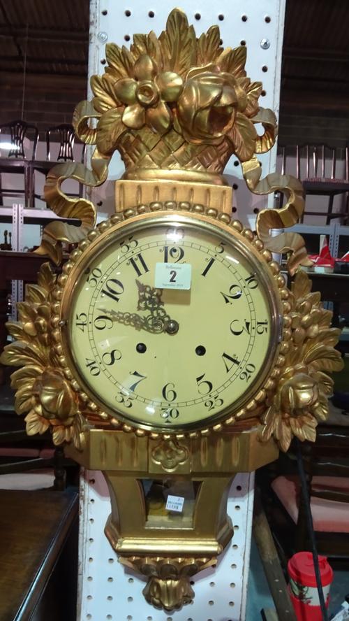 An early 20th century gilt painted eight day wall clock, with floral moulded decoration, 40cm high.