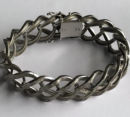A 9ct white gold wide bracelet of abstract interlinked textured design, fastened with a box and tongue clasp and safety links, detailed CJ Ltd, weight