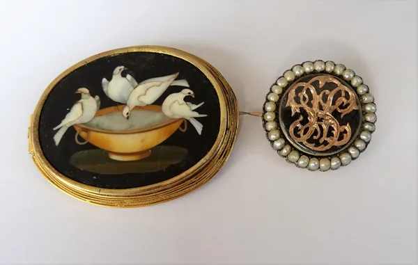 An oval Florentine pietra dura brooch, designed as Pliny's doves drinking from a cup, the mount decorated with a wirework border and a half pearl set