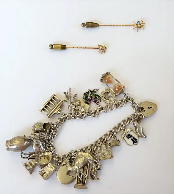 A silver curb link charm bracelet, fitted with a variety of mostly silver charms, including a camel, a boot and a Swiss cheese, on a heart shaped padl