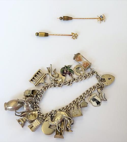 A silver curb link charm bracelet, fitted with a variety of mostly silver charms, including a camel, a boot and a Swiss cheese, on a heart shaped padl