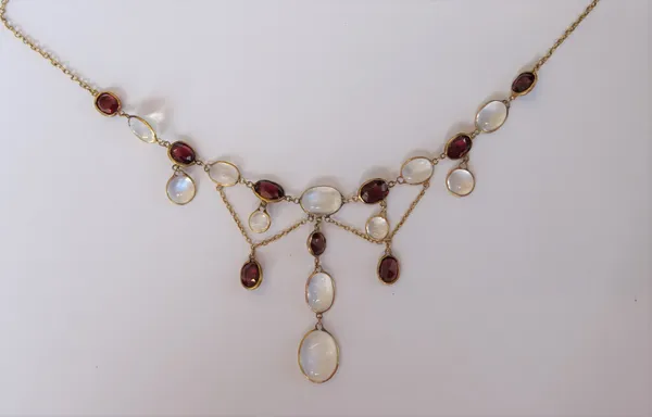 A gold, garnet and moonstone necklace, spectacle set with faceted garnets and with cabochon moonstones, the front with pendant drops on a tracelink ne