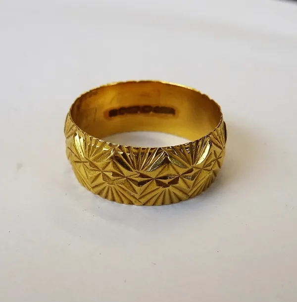 A 22ct gold wide band wedding ring, with facet cast decoration, London 1973, ring size Q and a half, weight 7 gms.