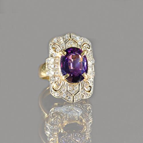 A gold, amethyst and diamond ring, in a curved panel shaped design, claw set with the oval cut amethyst to the centre and otherwise set with circular