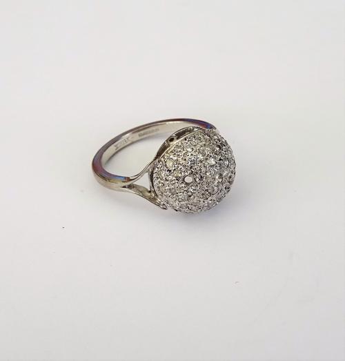 An 18ct white gold and diamond cluster ring, in a bombe design, mounted with circular cut diamonds, between diamond set split shoulders, (one diamond