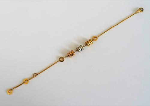 A Bvlgari 18ct three colour gold bracelet, the centre of the front with three barrel shaped motifs, with Bvlgari ring divisions at intervals, on a spr