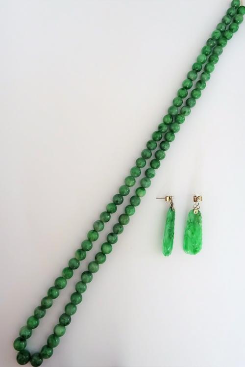 A single row necklace of graduated spherical jade beads, gross weight 75 gms and a pair of jade and seed pearl pendant earrings, each with a carved ja