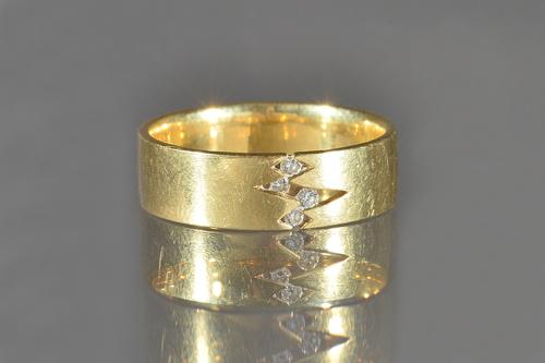 An 18ct gold and diamond set band ring, mounted with four circular cut diamonds in a zig-zag design, detailed Quinn 750 0.12 CT 9766, ring size Z and