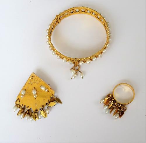 A gold and freshwater cultured pearl bangle, in an openwork design, spaced with freshwater cultured pearls to the centre, otherwise in an openwork des